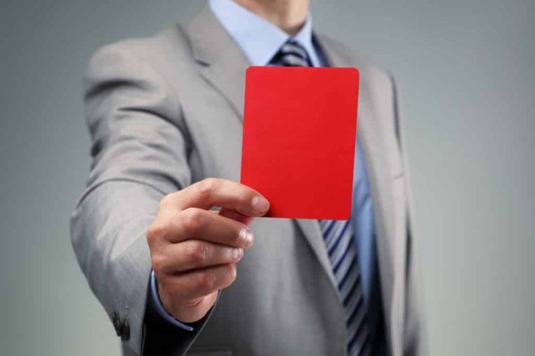 a man wearing a suit and tie showing a red card