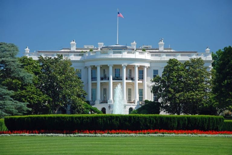 a large building with a grassy field with White House in the background