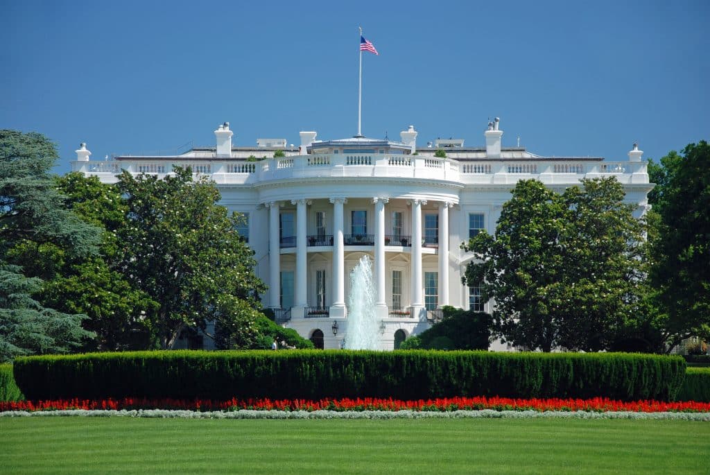 a large building with a grassy field with White House in the background