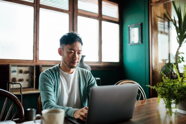 a man sitting at a table using a laptop a man sitting at a table using a laptop