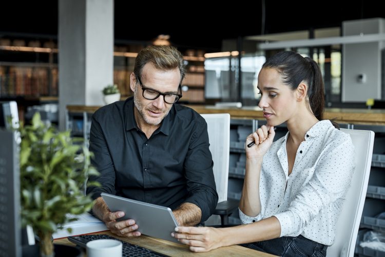 a man and a woman sitting at a table using a laptop a man and a woman sitting at a table using a laptop