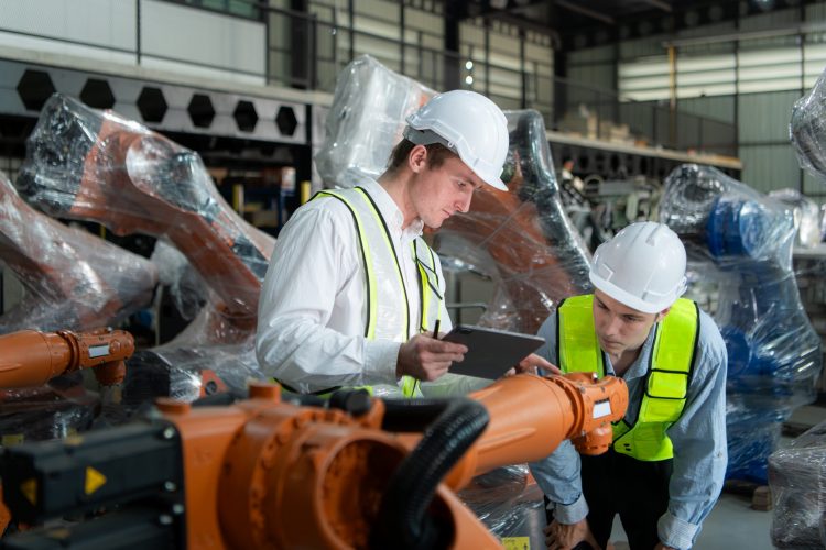Two engineers working together in a robotic arm factory,